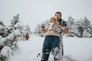 A couple enjoying playing in the snow together in a scenic forest during winter.
