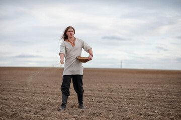 A young peasant sows the field with grain