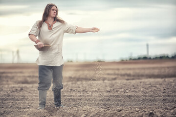 A young peasant sows the field with grain