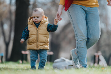 Adorable child strolling with adult guiding hand in serene park, symbolizing bonding, development,...