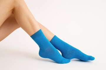Close-up of a woman with blue socks against a white backdrop