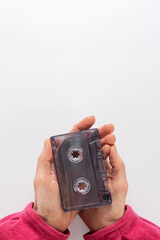 Old compact audio cassette in female hands on white background. Isolated hands holding an audio...
