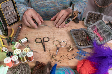 Man making trout flies. Fly tying equipment and material for fly fishing preparation .