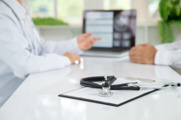 stethoscope on medical document with  doctor and patient discussing results of annual physica...
