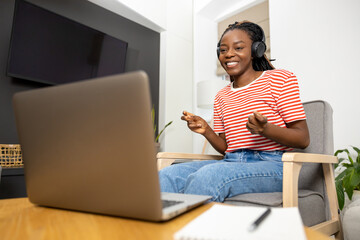 Smiling and contented young african american woman listening something online