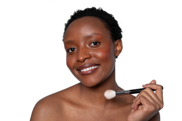Woman applying makeup with a brush in a bright studio setting, showcasing natural beauty and...