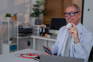 Experienced doctor in a modern office holding a medical device, explaining its use while using a...