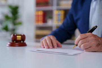 Lawyer signing a legal document with a gavel prominently placed in the foreground, highlighting the...