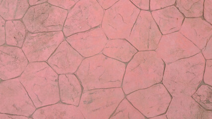 A pink cobblestone pavement with irregular shapes and dark gray grout lines, creating a textured...