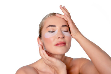 Woman applying skincare treatment with eye patches in a bright, clean setting during a wellness...