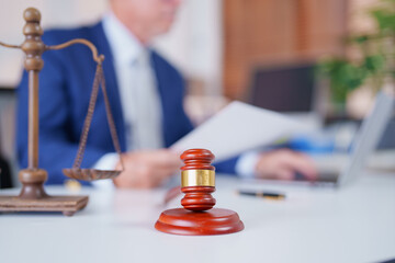 Focused legal professional reviews documents at a desk with a gavel and scales of justice,...