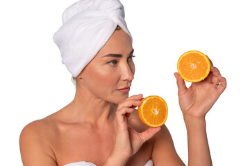 Woman holding orange slices while wearing a towel after a refreshing skincare routine at home
