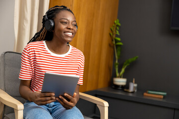 Young woman in headphones sitting at laptop and looking busy