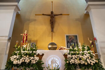 ołtarz z krzyżem  w tle przygotowany do liturgii w kościele katolickim