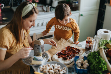 A mother and her child engage in preparing a homemade pizza in a cozy family kitchen, fostering creativity and bonding through the shared cooking experience.