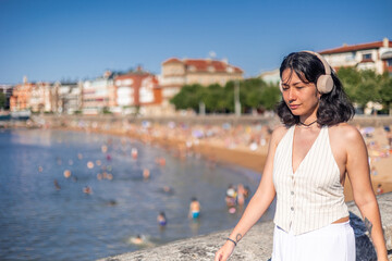 copyspace Young woman listening to music with headphones while enjoying summer near the beach