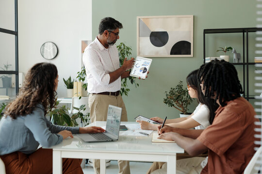 Manager leading a financial meeting with a diverse team in an office setting