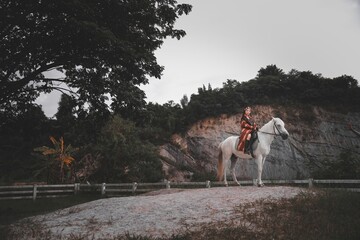 Woman Riding White Horse in Scenic Nature Setting with Dramatic Sky