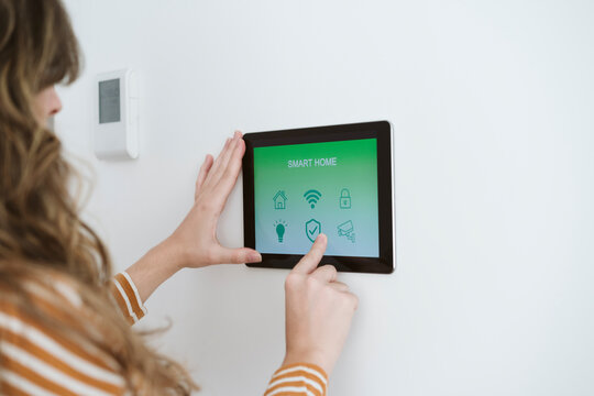 Close-up of woman using digital tablet with smart home app on the wall