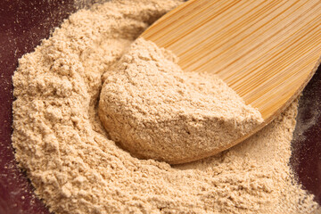 Ground Ashwagandha root in wooden bamboo spoon. Ayurvedic anti-stress supplement. Top view