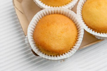 Vanilla muffins with paper cups in cardboard container. Top view