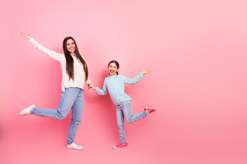 Smiling mother and daughter posing happily against a vibrant pink background showing care love and family bonding