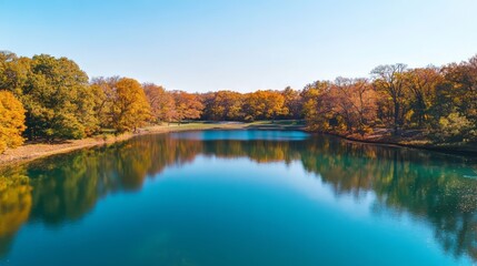 Fototapeta premium A lake with clear blue water and surrounding trees in autumn