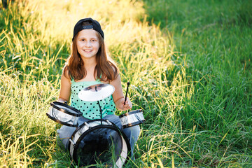 Happy caucasian kid girl drummer. Girl playing on elettronic drum kit or learns to play drums in music school. Emotional portrait. Free space for advertisement