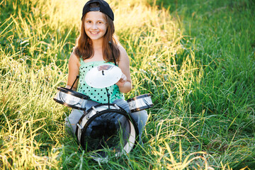 Happy caucasian kid girl drummer. Girl playing on drum kit. Emotional portrait. Cheerful little...