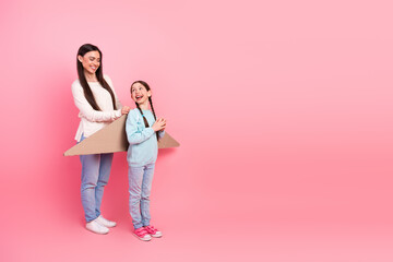 Mother and daughter enjoying creative playtime with cardboard on a pink background, highlighting family bonding