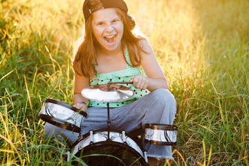 Happy caucasian kid girl drummer. Girl playing on drum kit or learns to play drums in music school. Emotional portrait. Free space for advertisement