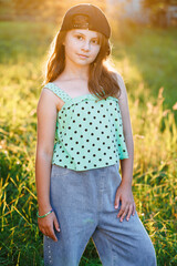 Happy cute little girl outdoors. Portrait of adorable preschool caucasian kid 8-9 years old standing in park over blurred background at sunset