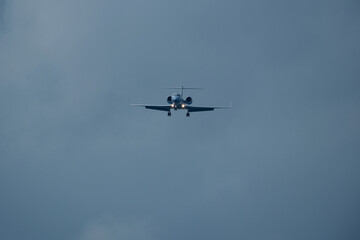 Private jet approaching the airport. Airplane in the cloudy sky.