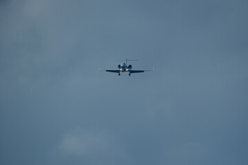Private jet approaching the airport. Airplane in the cloudy sky.