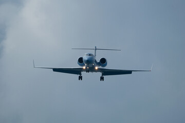 Private jet approaching the airport. Airplane in the cloudy sky.