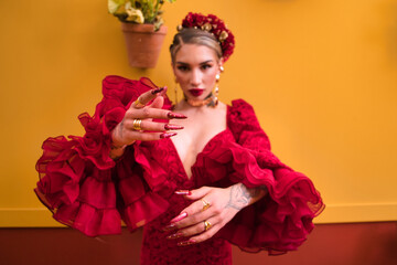 A beautiful woman dancing flamenco in a red ruffled dress with makeup and false nails against an...