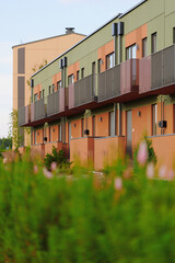 modern townhouses with colorful facades and balconies lined up amid green landscape reflecting...