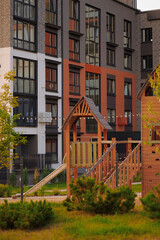 modern urban playground with wooden structures set against contemporary apartment building...