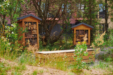 wooden insect hotels in lush green garden provide shelter for beneficial bugs and promote...