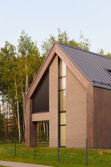 modern architecture brick house with tall windows in lush green setting. contemporary design with...