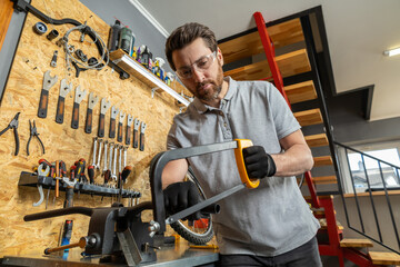 Velomechanic in professional attire servicing bicycle with specialized tools in workshop setting