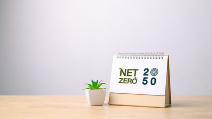 Desktop calendar showing “Net Zero 2050” with plant icon and target symbol. Concept of carbon neutrality, climate goal, ESG, and sustainable environmental commitment.