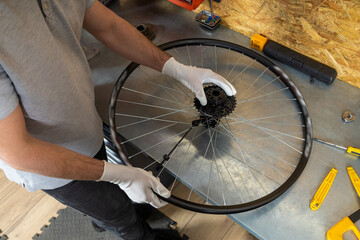 Skilled bike mechanic man using tools repairing bicycle in well-organized workshop