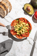 Avocado and tomato salad on kitchen countertop background