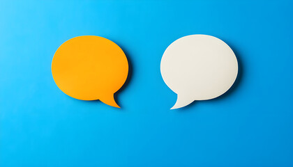 Two blank color paper speech bubbles for your design. White and orange dialogs on blue background. Flat lay top view, discussion template