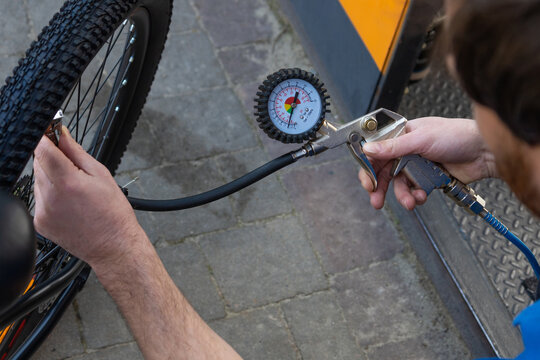 Mechanic in blue shirt pumping air into mountain bike tire using pump