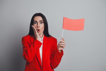 Confident businesswoman holding a red flag with a surprised expression concept for caution or...