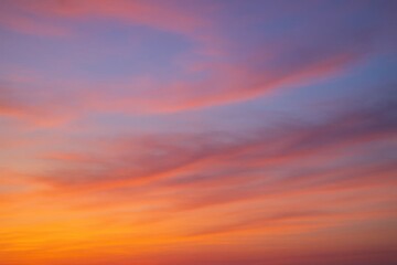 Obraz premium Radiant sunset sky displays a breathtaking gradient of warm orange, soft pink, and deep violet hues, creating a serene and captivating natural background.