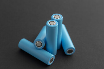 Stack of 18650 cylindrical batteries on black background, rechargeable lithium-ion batteries for electrical appliances and devices. Battery cell or secondary element.