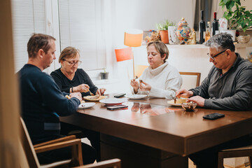 An intimate gathering of four individuals enjoying a meal at home, sharing moments of togetherness,...